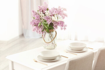 Glass vase with beautiful lilac flowers on table