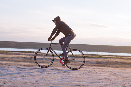 Alone rider on fixed gear road bike riding in the desert near river, hipster tourist bicycle rider pictures.