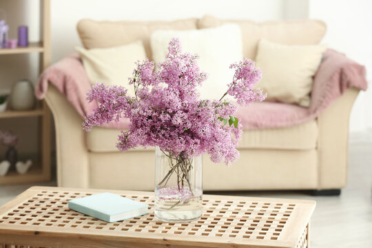 Glass vase with beautiful lilac flowers on table