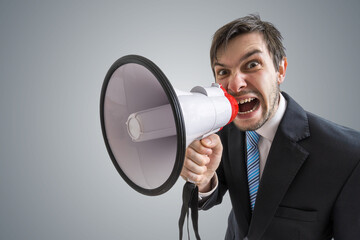 Young man is announcing a message and shouting to megaphone.