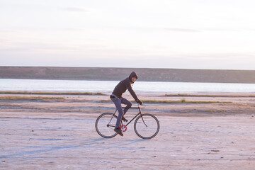 Alone rider on fixed gear road bike riding in the desert near river, hipster tourist bicycle rider pictures.