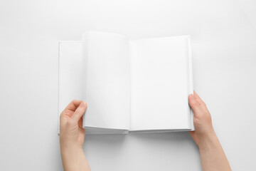 Female hands leafing through book with blank pages on light background