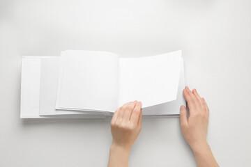 Female hands holding book with blank pages on white background