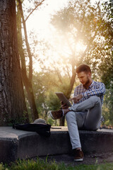Student with tablet computer working in the park