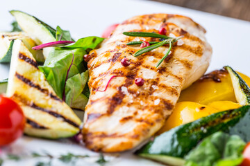 Grill chicken breast. Grilled vegetables with chicken breast. Grilled chicken with vegetables on oak table. © weyo