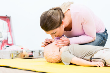 Woman in first aid course practicing revival of infant on baby doll