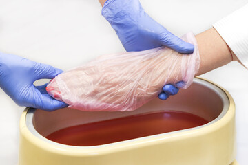 Process paraffin treatment of female hands in beauty salon 