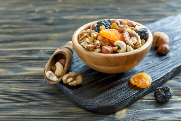 Mixture of nuts and dried fruit in a wooden bowl.