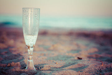 une coupe de champagne en plastique posée dans le sable d'une plage, couleur vintage