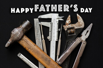 happy father's day text sign with many working tools on black rustic background top view. fathers...