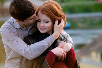 Fototapeta premium Redhead pretty girl in hugs of handsome brunette man, romantic moment