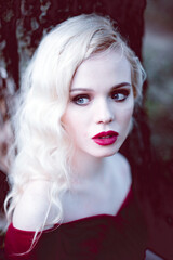 Fashion gorgeous young blonde woman in beautiful red dress in a fairy-tale forest. magic atmosphere. toning shot