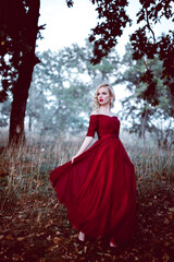 Obraz na płótnie Canvas Fashion gorgeous young blonde woman in beautiful red dress in a fairy-tale forest. magic atmosphere. toning shot