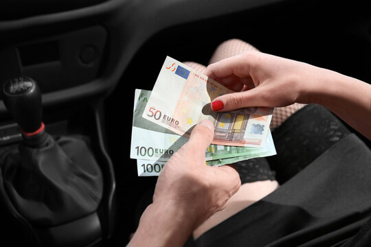 Young prostitute receiving money from client in car