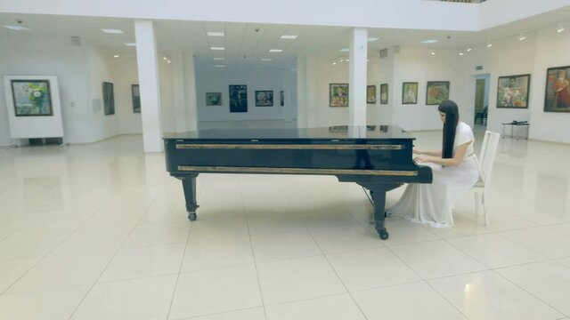 Beautiful girl playing the piano in picture gallery