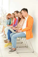 Young people with laptops sitting on chairs