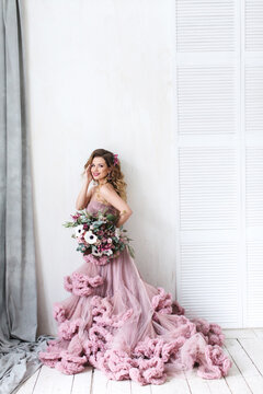 Woman with long curly hair in a pink dress and Wedding Flowers.