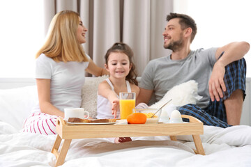 Obraz na płótnie Canvas Happy family sitting on bed with breakfast