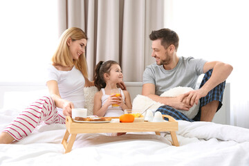 Happy family sitting on bed with breakfast - Powered by Adobe