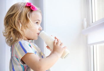 Cute little girl drinking yogurt at home