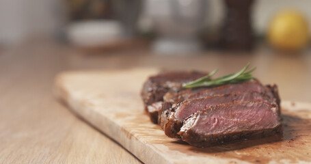 sliced medium rib eye steak with rosemary branch, wide photo