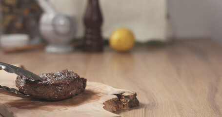 medium rib eye steak being put on board with tongs, wide photo