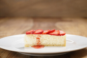 cheesecake with strawberry on plate on wood table, shallow focus