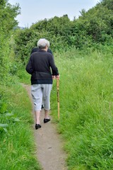 Une femme âgée pratique la randonnée sur le sentier côtier en Bretagne