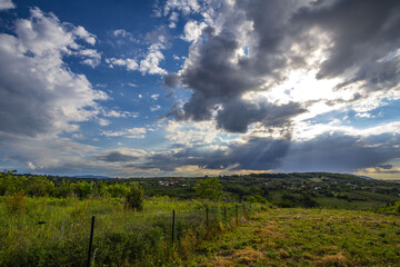 Typical European continental countryside taken in Balkans, in Serbia, during a spring afternoon, sun being progressively hidden by grey clouds and rain..