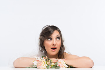 Surprised and amazed young woman bride in bridal dress with flowers