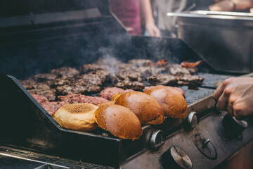 Cooking delicious juicy meat burgers and buns on the grill