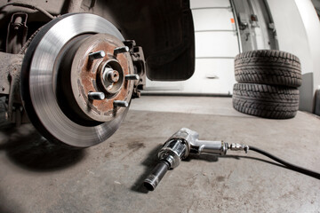 Closeup disc brake of the vehicle for repair. shot wheel, the tool for loosening the nuts. internal...