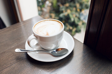 Hot art Latte Coffee in a cup on wooden table and Coffee shop blur background with bokeh image
