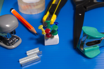 Stationery on a green background, eraser, buttons, paperclips, ruler, clamp, stapler, sharpener