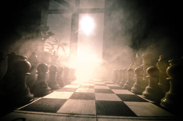 Naklejka premium chess board game concept of business ideas and competition and strategy ideas concep. Chess figures on a dark background with smoke and fog. Selective focus. Hand puts figure on board