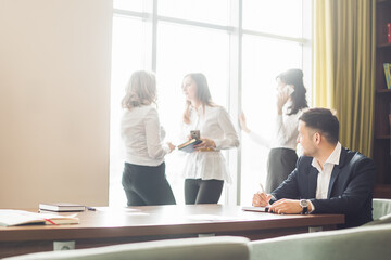 Businessman in dark suit and blue shirt sitting at office desk signing a contract with shallow focus on signature.