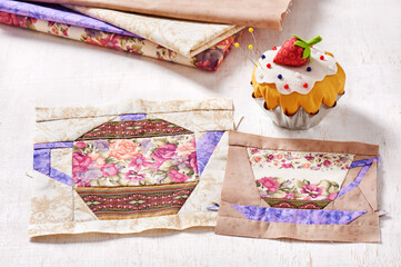 Patchwork blocks of the cup and the teapot with a pattern of flowers and the pin cushion like a cupcake with strawberry