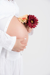 Pregnant woman with yellow and red flowers holding next to her belly ready to give birth