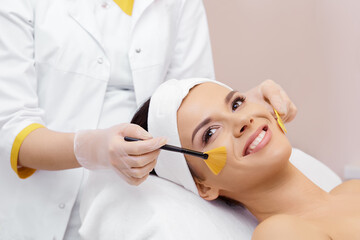 Naklejka premium Cosmetology. Spa clinic. Beautiful woman at facial treatment procedure. Young healthy skin. Facial mask. Skin rejuvenation.