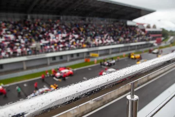 Foto op Plexiglas Racing cars on the starting grid. The focus on the handrail with rain drops © shishkin137