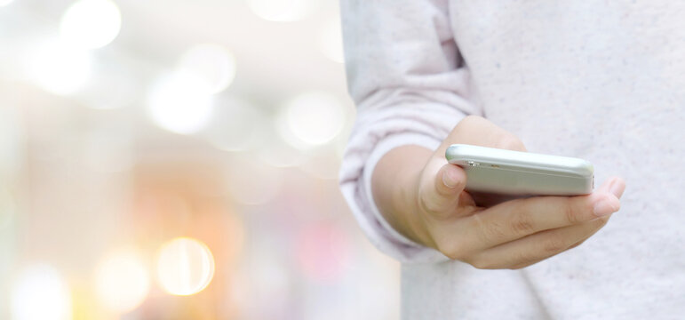 Hand using smart phone over blur bokeh light background, business and technology concept, digital marketing, seo, e-commerce, network, internet of things