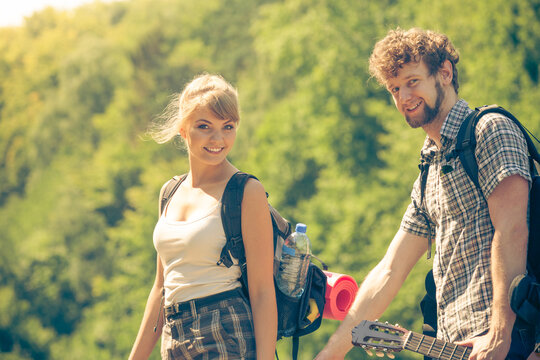 Hiking young couple with guitar backpack outdoor