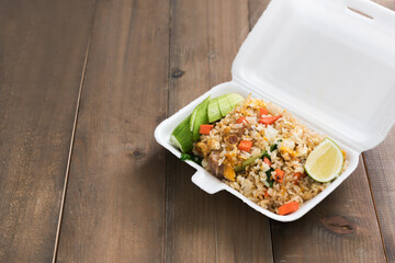 Hot food in foam box on wood table