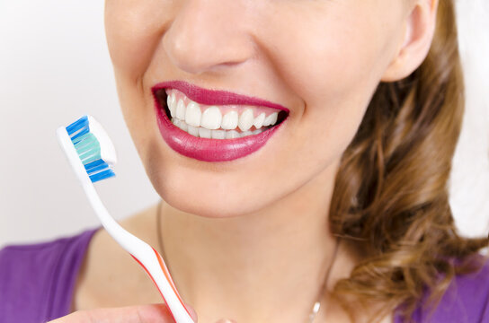 Closeup on mouth of perfect teeth woman smiling and holding toothbrush 
