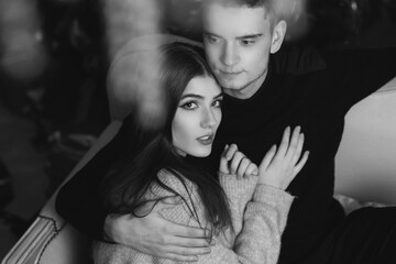 Closeup portrait of young romantic caucasioan couple sitting and higging in christmas decorated...