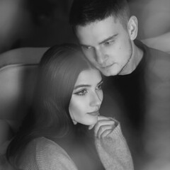 Closeup portrait of young romantic caucasioan couple sitting and higging in christmas decorated...