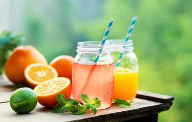 Crédence de cuisine en verre imprimé Jus Jus de pamplemousse et d& 39 orange dans des bocaux en verre à l& 39 air libre.