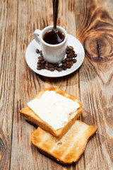 Breakfast with coffee, toasts, butter and jam on white wooden background