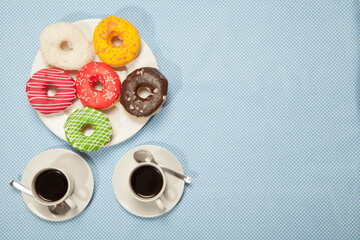 Two cups with coffee and donuts on a blue table