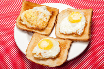Toasts and eggs on a plate on a red table